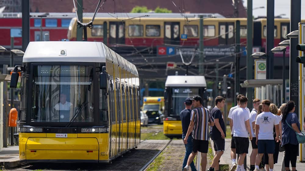 Eine Straßenbahn der BVG steht an einer Haltestelle am Alexanderplatz, während im Hintergrund eine S-Bahn und eine Regionalbahn vorbeifahren. / Foto: Monika Skolimowska/dpa