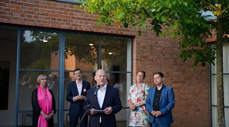 Bundeskanzler Olaf Scholz (M, SPD) besucht ein Sommerfest zum 25. Jubiläum des Vereins Freunde und Förderer des Mies van der Rohe Hauses und spricht dabei zu den Gästen und anwesenden Journalisten. / Foto: Markus Schreiber/Pool AP/dpa