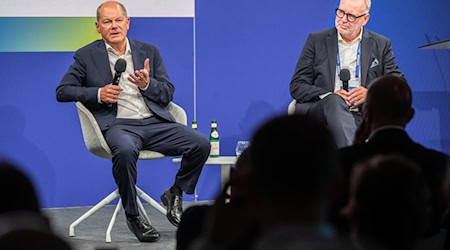 Bundeskanzler Olaf Scholz (l, SPD) und Frank Nehring, Präsident Ostdeutsches Wirtschaftsforum (OWF) sitzen beim Ostdeutschen Wirtschaftsforum im Theater am See auf der Bühne. / Foto: Monika Skolimowska/dpa