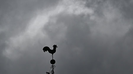 Über einem Wetterhahn schweben dunkle Regenwolken. / Foto: Bernd Weißbrod/dpa