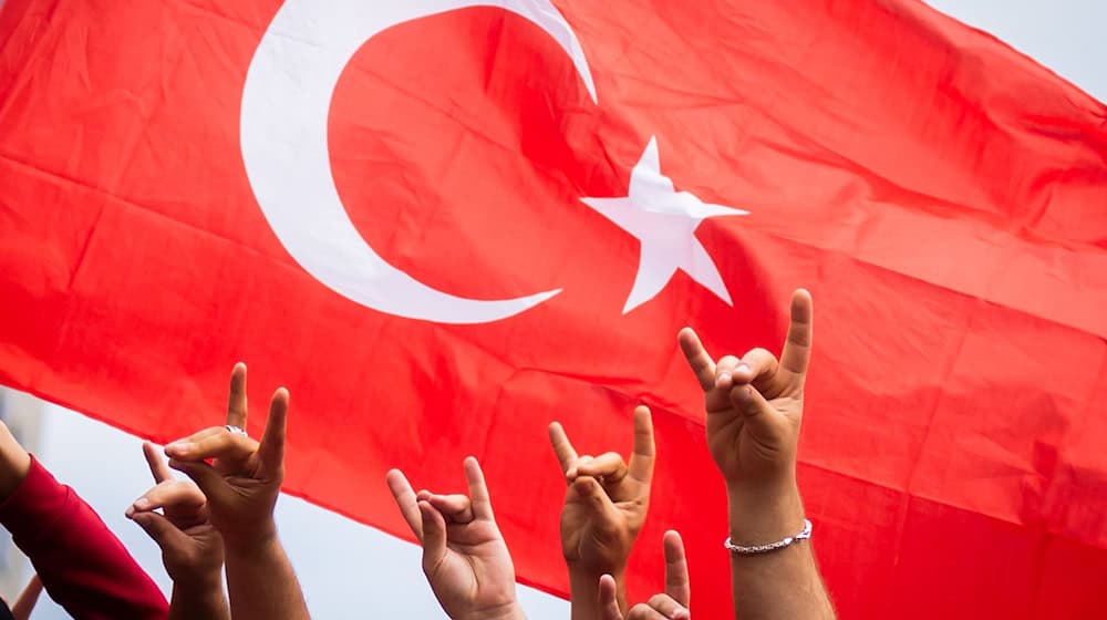 Türkei-Fans zeigen beim Fanmarsch Richtung Olympiastadion den «Wolfsgruß». / Foto: Christoph Soeder/dpa