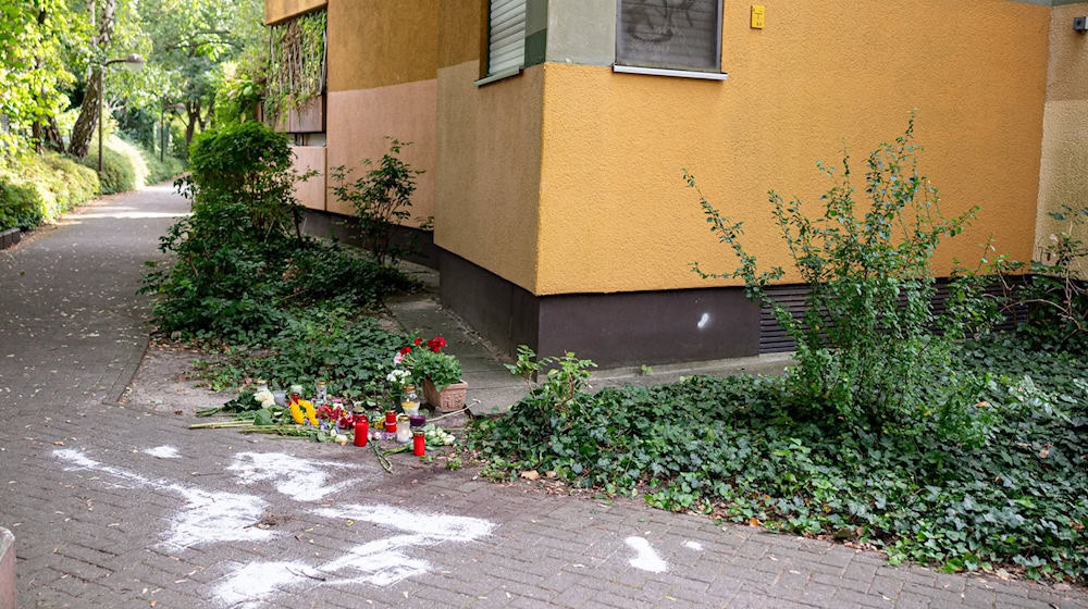 Kerzen und Blumen stehen und liegen in Berlin-Zehlendorf an dem Ort, an dem mutmaßlich ein Mann seine Ex-Frau erstochen haben soll. (Archivbild) / Foto: Fabian Sommer/dpa