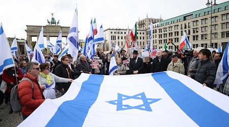 Teilnehmer einer proisraelischen Demonstration am 6. Oktober halten gemeinsam eine große israelische Flagge. / Foto: Jörg Carstensen/dpa