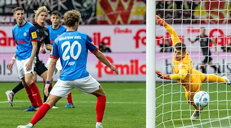 Union Berlins Tom Rothe (2. v l) trifft zum 0:2 gegen Kiels Torwart Timon Weiner (r). / Foto: Axel Heimken/dpa