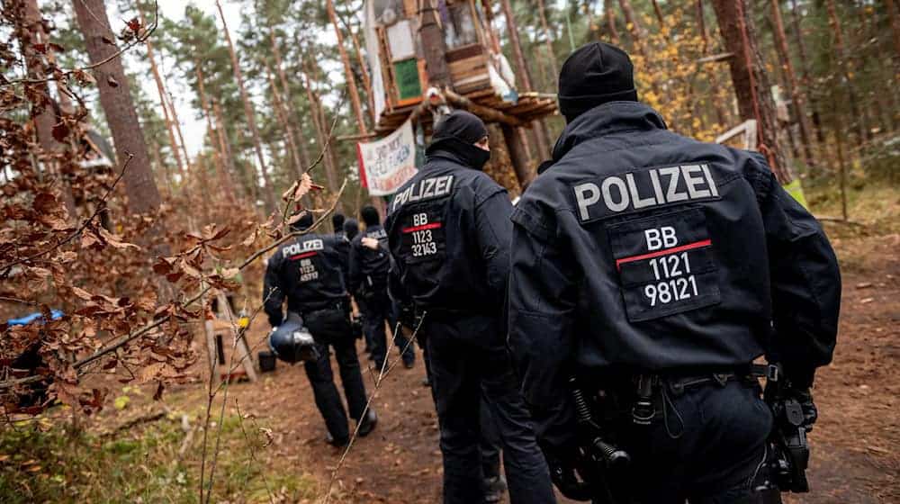 Polizeikräfte sperren ein Waldgebiet, in dem das Tesla-Protestcamp in Grünheide bei Berlin liegt. / Foto: Fabian Sommer/dpa