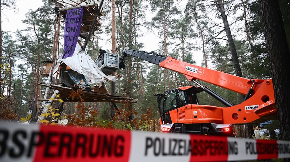 Mit Hilfe einer Hebebühne kommen die Polizeikräfte an die Baumhäuser im aufgelösten Tesla-Protestcamp heran.  / Foto: Sebastian Christoph Gollnow/dpa