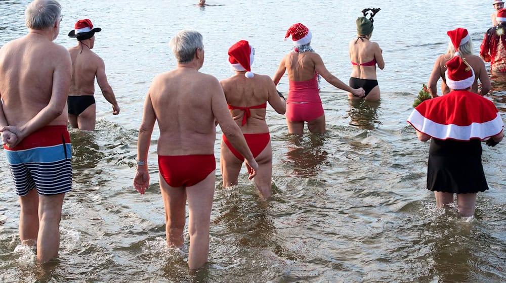 Dutzende Badefreunde gehen am ersten Weihnachtsfeiertag in den kalten Orankesee. / Foto: Paul Zinken/dpa