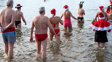 Dutzende Badefreunde gehen am ersten Weihnachtsfeiertag in den kalten Orankesee. / Foto: Paul Zinken/dpa