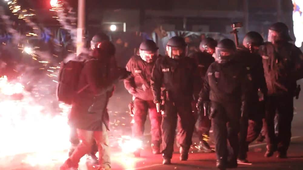 Polizisten stehen zwischen brennendem Feuerwerk in Neukölln. (Foto aktuell) / Foto: Julius Schreiner/dpa