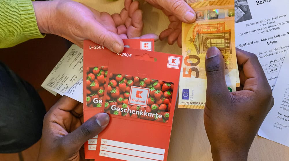 Ein Flüchtling tauscht zwei im Supermarkt gekaufte Gutscheine gegen Bargeld. / Foto: Patrick Pleul/dpa