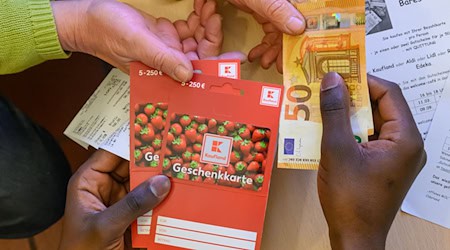 Ein Flüchtling tauscht zwei im Supermarkt gekaufte Gutscheine gegen Bargeld. / Foto: Patrick Pleul/dpa