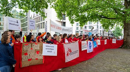 Mitarbeiter von Hilfsorganisationen demonstrieren in Berlin für mehr Hilfsgüter in Gaza.   / Foto: Soeren Stache/dpa