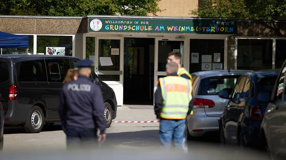 Polizisten stehen vor einer Schule im Berliner Bezirk Spandau, an der es am Vormittag einen möglichen Messerangriff auf einen Schüler gab. / Foto: Jörg Carstensen/dpa