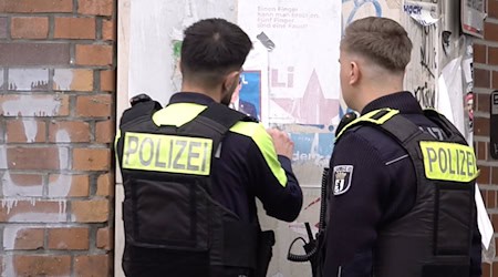 Zwei Polizisten entfernen ein Plakat, das den am Mittwoch erschossenen Deutsch-Israeli Yaron Lischinsky zeigt. / Foto: Sven Kaeuler/dpa