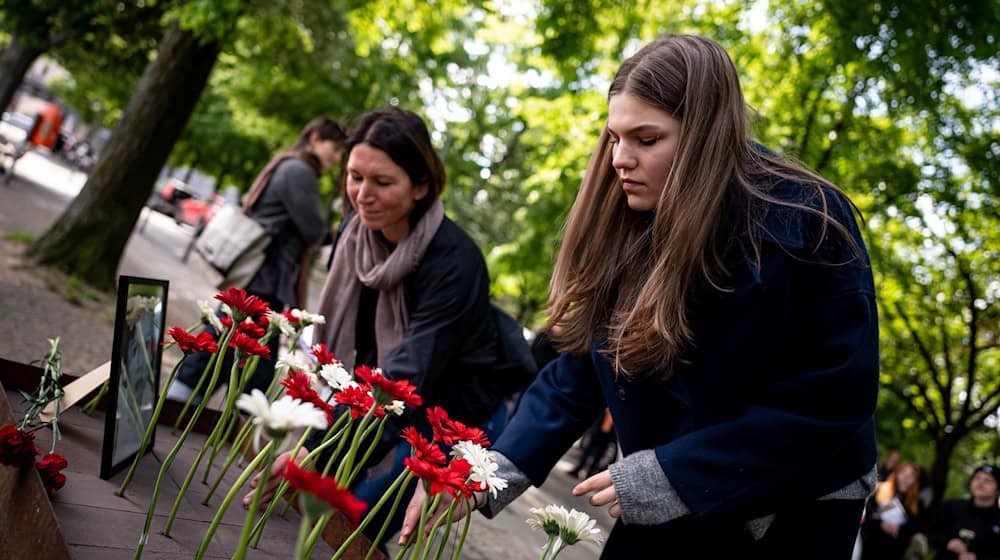 Menschen legen bei der Gedenkveranstaltung zu Çetin Merts Tod vor 50 Jahren Blumen vor die Gedenktafel. / Foto: Fabian Sommer/dpa