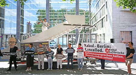 Aktivsten stehen während einer symbolischen Protestaktion am Weltflüchtlingstag zur Unterstützung mehrerer Klagen von Afghanen gegen die Bundesregierung vor dem Auswärtigen Amt. / Foto: Michael Brandt/dpa