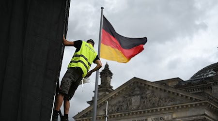 Die Aufbauarbeiten laufen: Ein Arbeiter befestigt eine Plane zur Vorbereitung einer Projektion anlässlich des 30. Jahrestags der Reichstag-Verhüllung. / Foto: Jennifer Brückner/dpa