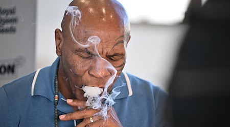 Box-Ikone und Cannabis-Unternehmer Mike Tyson raucht an einem Stand der Cannabis-Messe Mary Jane einen Joint.  / Foto: Sebastian Gollnow/dpa