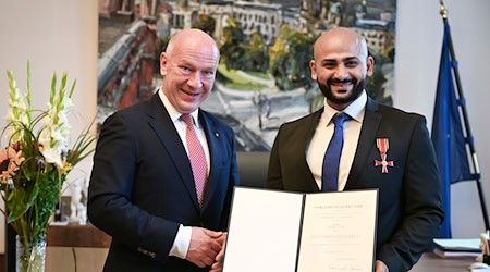 Kai Wegner hat Yousef Ayoub das Bundesverdienstkreuz samt Urkunde überreicht.  / Foto: Jens Kalaene/dpa