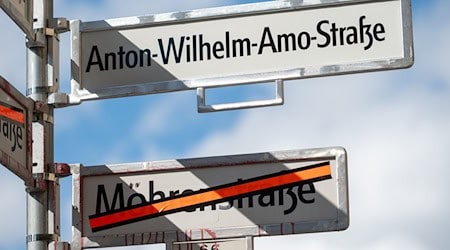 Ein Schild mit der Aufschrift «Anton-Wilhelm-Amo-Straße» hängt über einem Schild, auf dem der Name «Mohrenstraße» durchgestrichen ist.  / Foto: Christophe Gateau/dpa