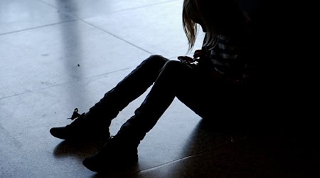 Ein kleines Mädchen sitzt mit gesenktem Kopf allein auf dem Fußboden. (Symbolbild)  / Foto: Britta Pedersen/dpa-Zentralbild/dpa