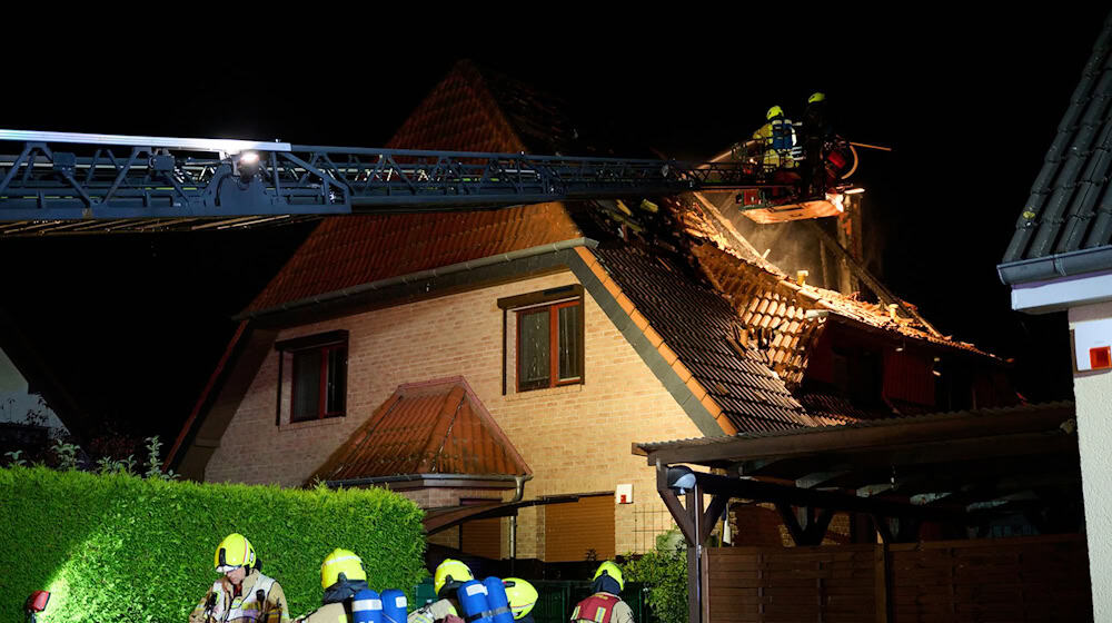 Einsatzkräfte der Feuerwehr stehen auf einer Feuerwehrleiter und löschen einen Brand in Marzahn. (Archivbild)  / Foto: Annette Riedl/dpa