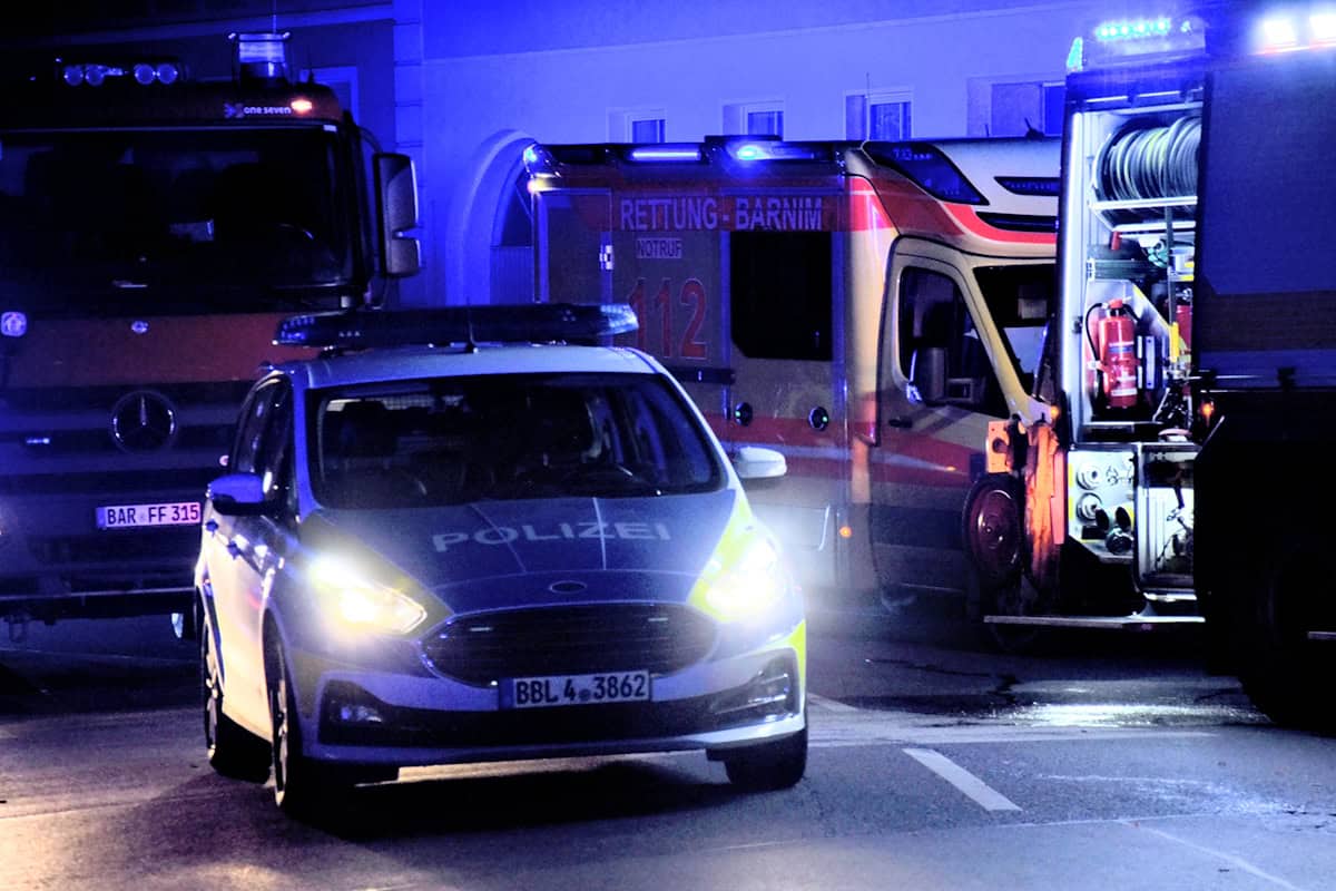 Polizeiauto mit eingeschaltetem Blaulicht und Feuerwehrfahrzeuge bei nächtlichem Einsatz an Unfallstelle. Polizeiauto mit eingeschaltetem Blaulicht und Feuerwehrfahrzeuge bei nächtlichem Einsatz an Unfallstelle.