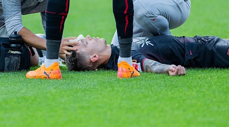 Bayer Leverkusens Kapitän Alejandro Grimaldo liegt nach einem Zusammenprall auf dem Boden.  / Foto: Rolf Vennenbernd/dpa