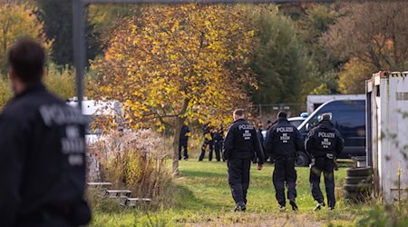 Polizisten stehen bei dem Großeinsatz auf einem Grundstück. (Archivbild)  / Foto: Christophe Gateau/dpa