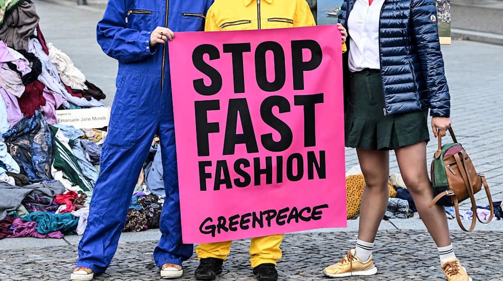 Die Umweltschützer wollen mit der Kunst-Aktion ein Zeichen gegen Müllberge aus Klamotten setzen, für die sie die Modeindustrie mitverantwortlich machen. / Foto: Jens Kalaene/dpa