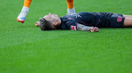 Bayer Leverkusens Kapitän Alejandro Grimaldo liegt nach einem Zusammenprall mit dem eigenen Mann benommen auf dem Boden.  / Foto: Rolf Vennenbernd/dpa