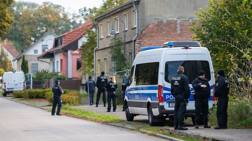 Polizisten stehen vor einem Grundstück in Tauche. / Foto: Christophe Gateau/dpa
