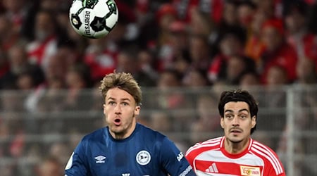 Bielefelds Kunze (l.) und Union Leite (r.) visieren den Ball an.  / Foto: Soeren Stache/dpa Bielefelds Kunze (l.) und Union Leite (r.) visieren den Ball an.  / Foto: Soeren Stache/dpa