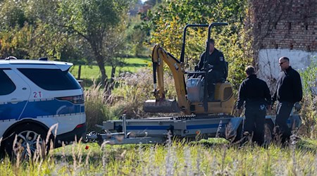 Polizisten untersuchen mit einem Bagger ein Grundstück in Herzberg (Landkreis Oder-Spree). / Foto: Christophe Gateau/dpa