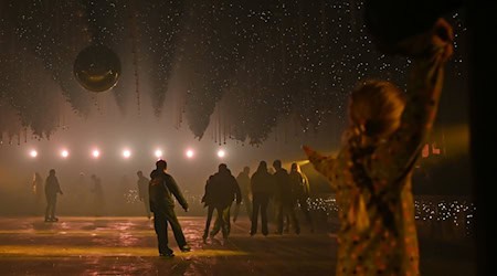 Besucher laufen auf der Eisfläche der Kunst-Lichtinstallation „Dark Matter: Forest Winterlights“.  / Foto: Elisa Schu/dpa