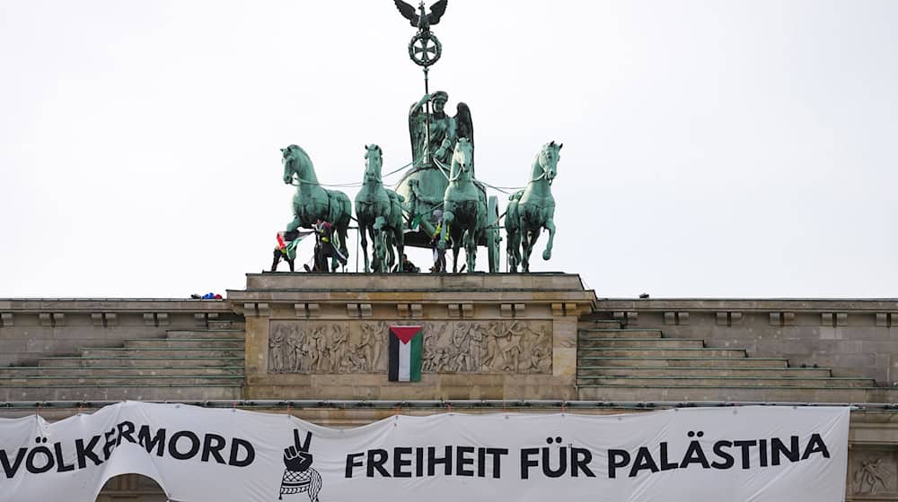 Mehrere Demonstranten sind auf das Brandenburger Tor in Berlin geklettert und haben ein israelfeindliches und propalästinensisches Transparent aufgehängt. / Foto: Kay Nietfeld/dpa