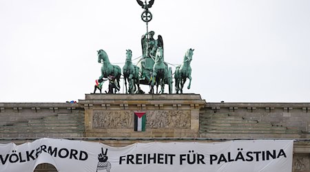 Mehrere Demonstranten sind auf das Brandenburger Tor in Berlin geklettert und haben ein israelfeindliches und propalästinensisches Transparent aufgehängt. / Foto: Kay Nietfeld/dpa