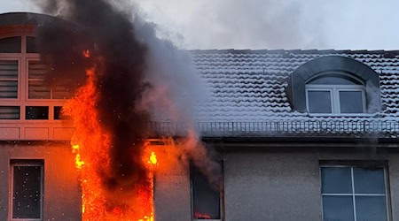 Feuer schlägt während eines Brandes aus dem Fenster eines Hauses. / Foto: Sebastian Gollnow/dpa