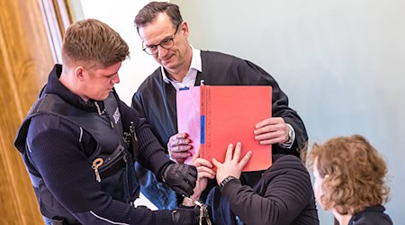 Auch am zweiten Verhandlungstag im Prozess um einen tödlichen Polizei-Einsatz gegen Autodiebe verdeckt der Angeklagte sein Gesicht.  / Foto: Frank Hammerschmidt/dpa