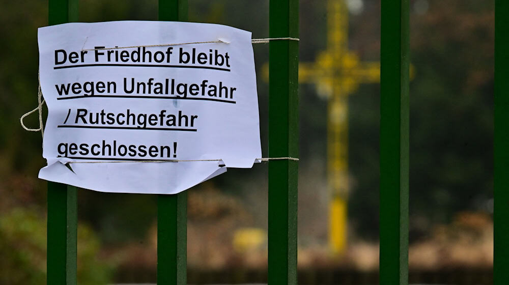 «Der Friedhof bleibt wegen Unfall / Rutschgefahr geschlossen!» steht an einem Eingang des Friedhofs St. Johannes-Evangelist.  / Foto: Sebastian Christoph Gollnow/dpa