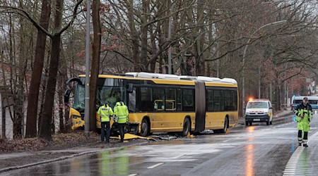 Polizisten stehen an der Unfallstelle vor dem beschädigten Bus. / Foto: Carsten Koall/dpa