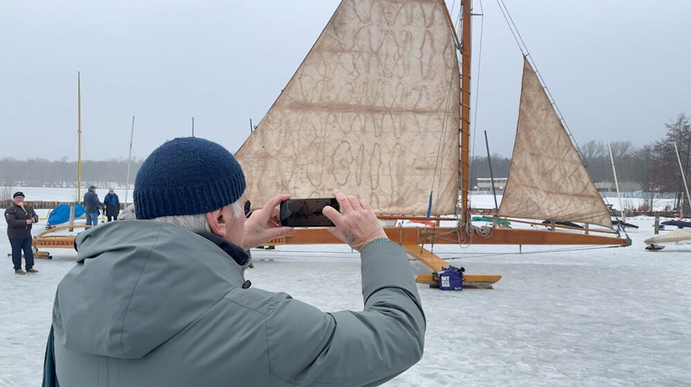 Ein Mann fotografiert auf dem zugefrorenen Müggelsee einen großen Eissegler.  / Foto: Lutz Deckwerth/dpa