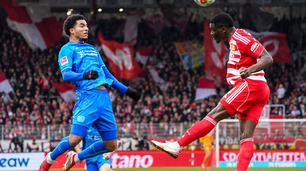 Union Berlins Nsoki (r.) setzt sich im Kopfballduell mit Leverkusens Tillmann (l.) durch.  / Foto: Soeren Stache/dpa