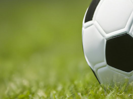 Nahaufnahme eines klassischen schwarz-weißen Fußballs auf grünem Rasen – Symbol für die FIFA Weltmeisterschaft 2026