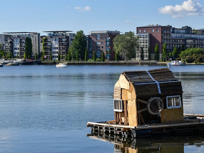 Ein Floß mit einem zusammengezimmerten Holzhaus schwimmt auf dem Rummelsburger See. (Archivbild)  / Foto: Jens Kalaene/dpa-Zentralbild/ZB
