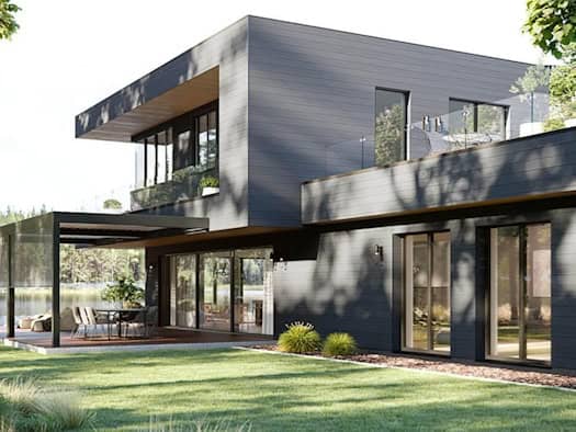 Modernes Haus mit großen Glasflächen und Hebe-Schiebe-Türen, die den Übergang zur Terrasse und zum Garten fließend gestalten