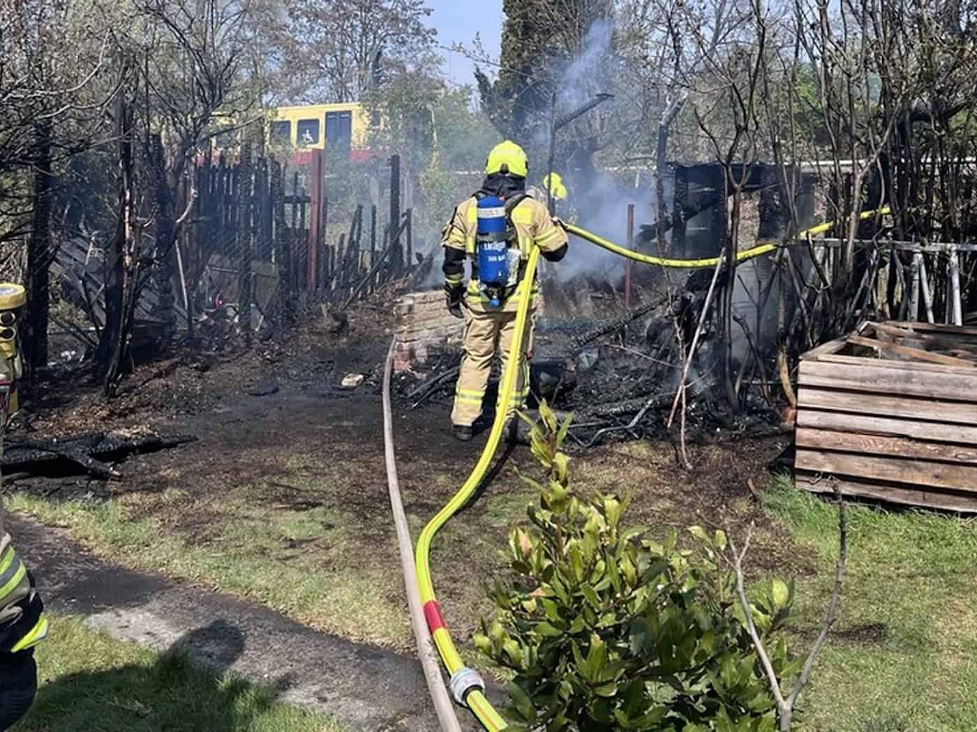 Einsatzkräfte der Feuerwehr löschen den Brand zweier Gartenhäuser. (Handout)  / Foto: ---/Berliner Feuerwehr/dpa