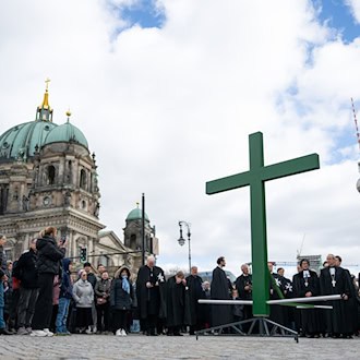 Bei der Karfreitagsprozession wurde auch dieses Jahr wieder ein goßes grünes Kreuz durch die Innenstadt getragen. / Foto: Christophe Gateau/dpa