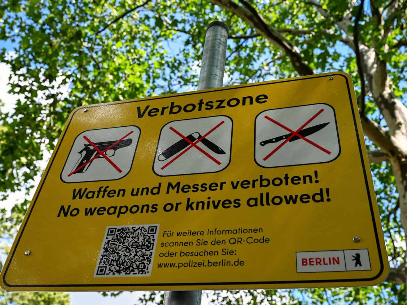 Ein Schild mit der Aufschrift «Verbotszone Waffen und Messer verboten! No weapons or knives allowed!» hängt am Görlitzer Park. (Archivbild)  / Foto: Soeren Stache/dpa