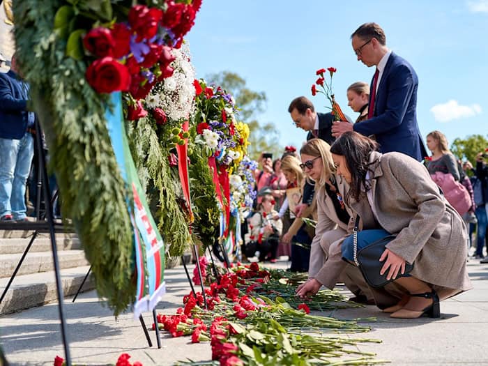 Menschen haben rote Blumen niedergelegt.  / Foto: Michael Ukas/dpa